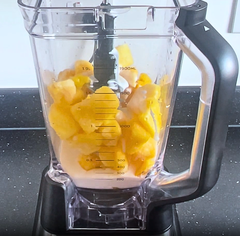 ninja blender with pineapple chunks and coconut milk