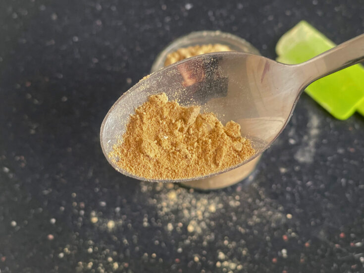 spoon with coconut sugar icing sugar in front of jar of coconut icing sugar