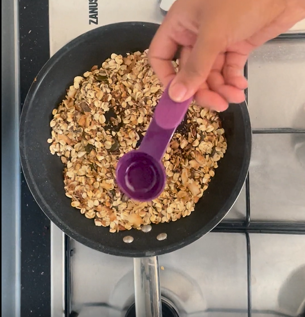 Adding coconut oil to toasted ingredients in hot non-stick frying pan