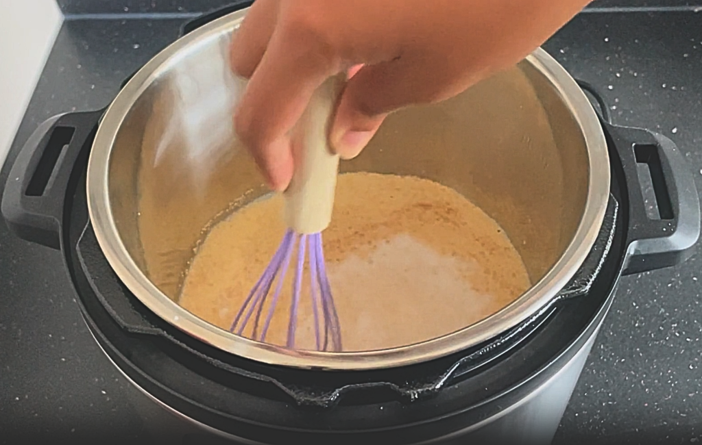 Whisk being used to stir the contents of the Instant Pot