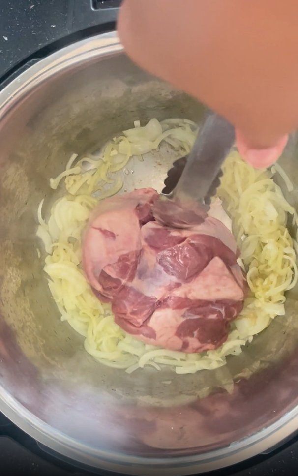 Adding lamb to the well of the Instant Pot ensuring the seasoned side is down