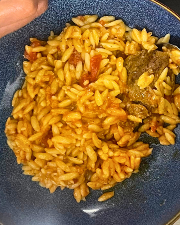 Lamb orzo plate with hand on spoon