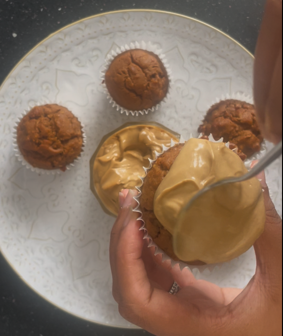 Putting a spoonful of the coconut sugar cream cheese on a carrot cake muffin