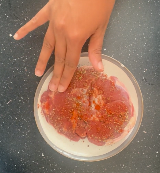 Rubbing in seasoning on the lamb that is on a saucer