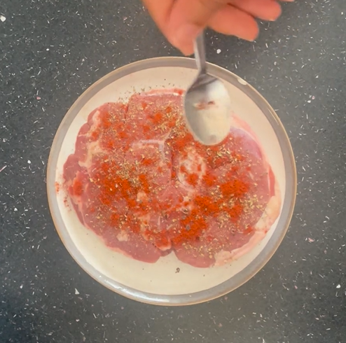 Seasoning lamb with freshly ground black pepper on saucer