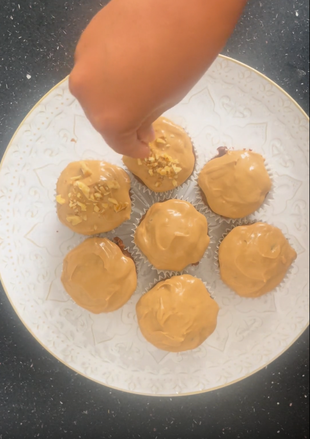 Using chopped pecans to decorate the top of the iced carrot cake muffins