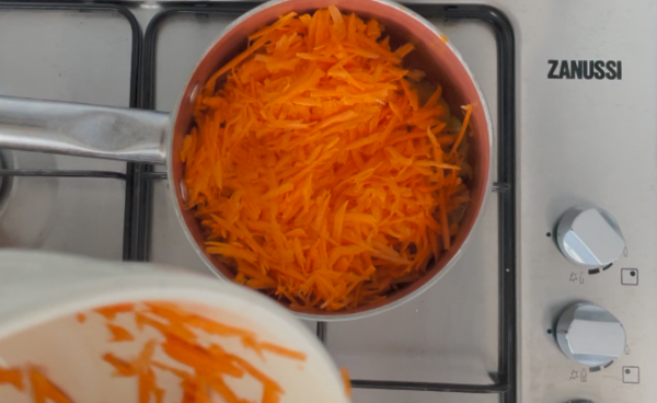 Adding grated carrots to pot