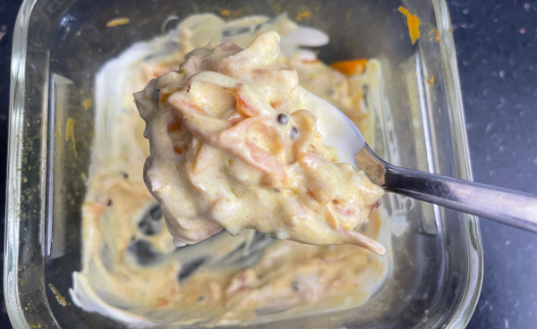 Carrot raita on a teaspoon over the bowl of carrot raita