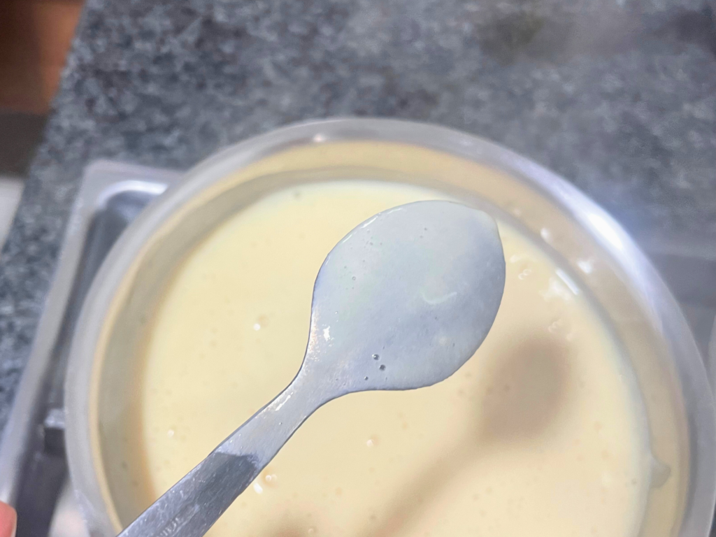 Custard on back of a spoon over a pot of custard