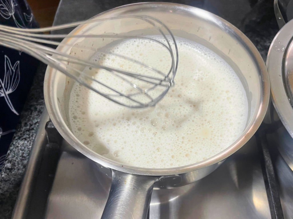 Hot milk in pot after being whisked so there is froth on the top