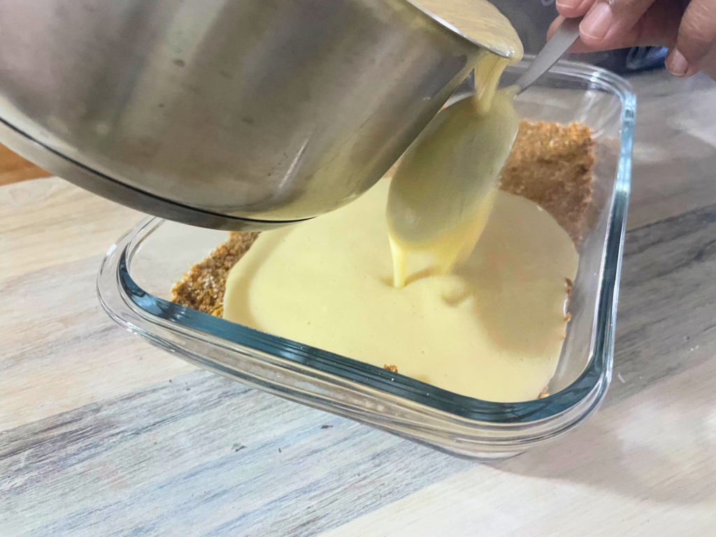 Melk tert custard being poured onto base via back of a spoon