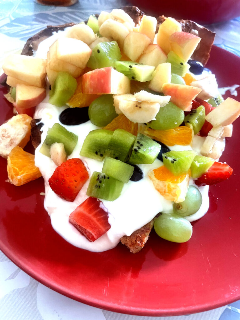 fruit-loaded on dutch baby that is on the red plate, most vibrant and colourful
