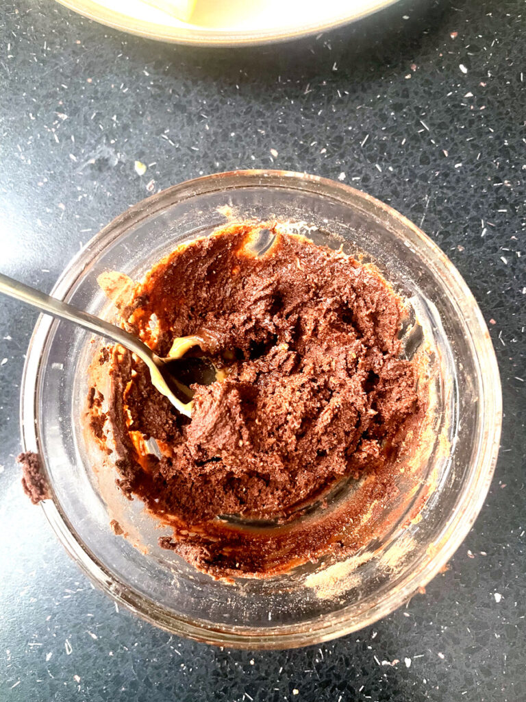 Chocolate peanut butter dip being mixed with a spoon in a glass bowl