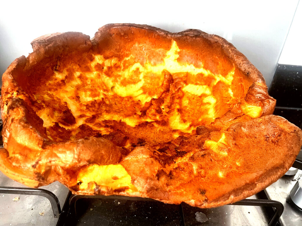 dramatic side view showing the rise of the dutch baby, clean white tile background